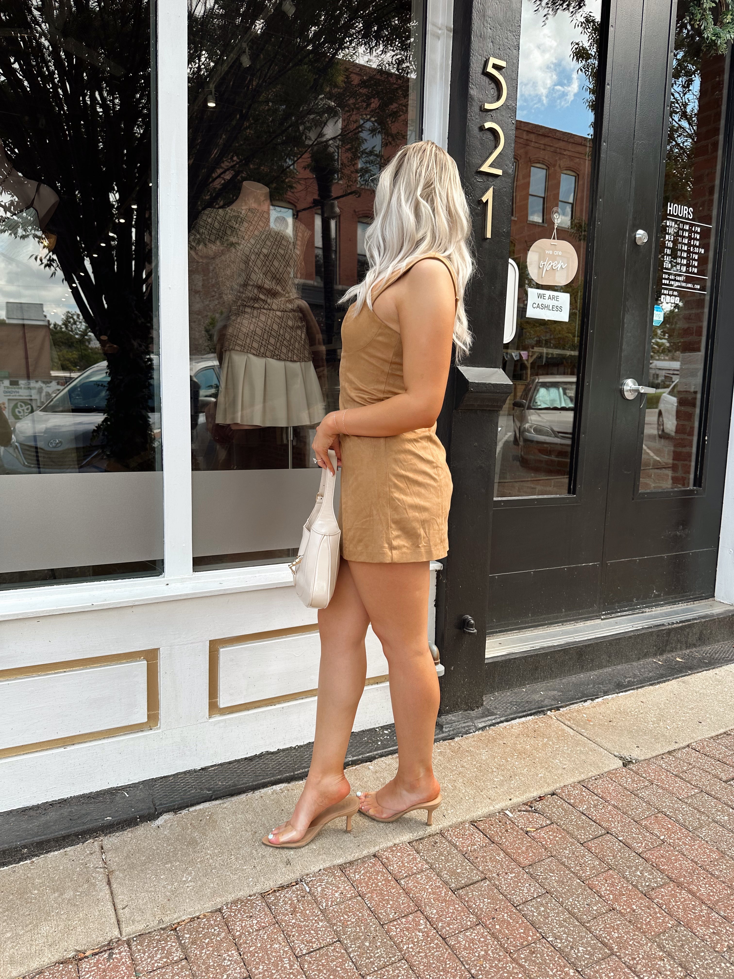 Woman wearing a tan suede sleeveless mini dress with adjustable straps.