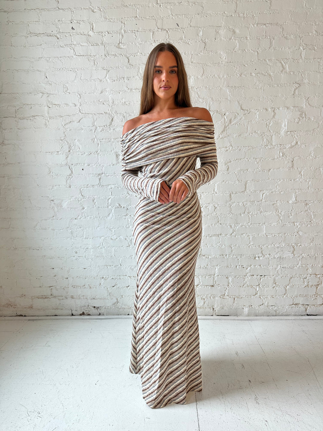 Woman wearing neutral striped fold over knit maxi dress with long sleeves.