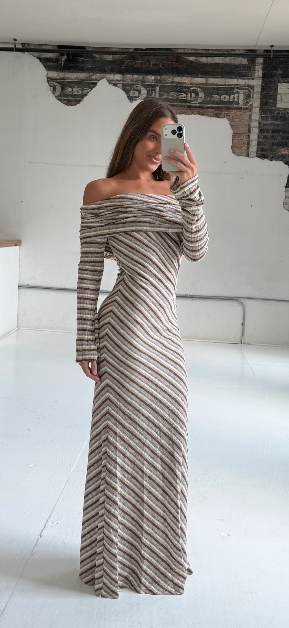 Woman wearing neutral striped fold over knit maxi dress with long sleeves.