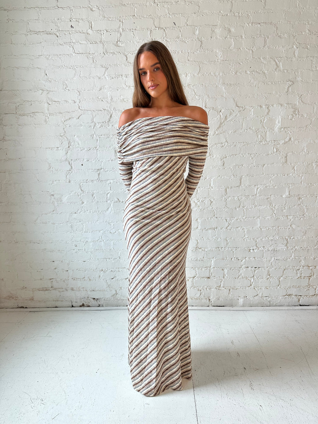 Woman wearing neutral striped fold over knit maxi dress with long sleeves.