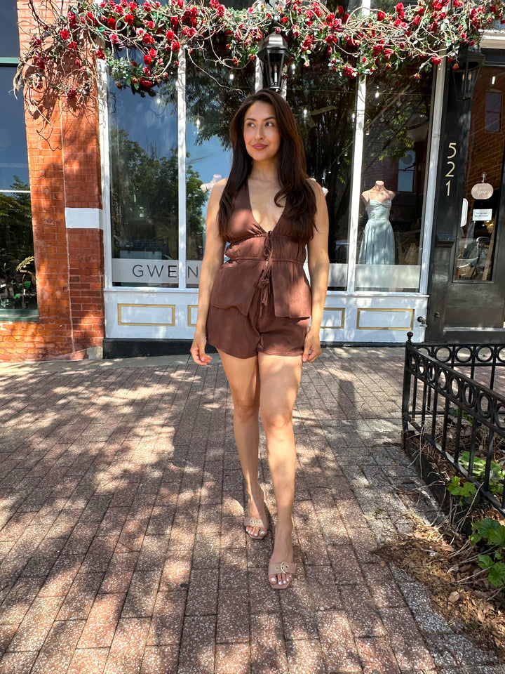 Woman wearing chocolate brown two piece set with front tie top, and shorts.  