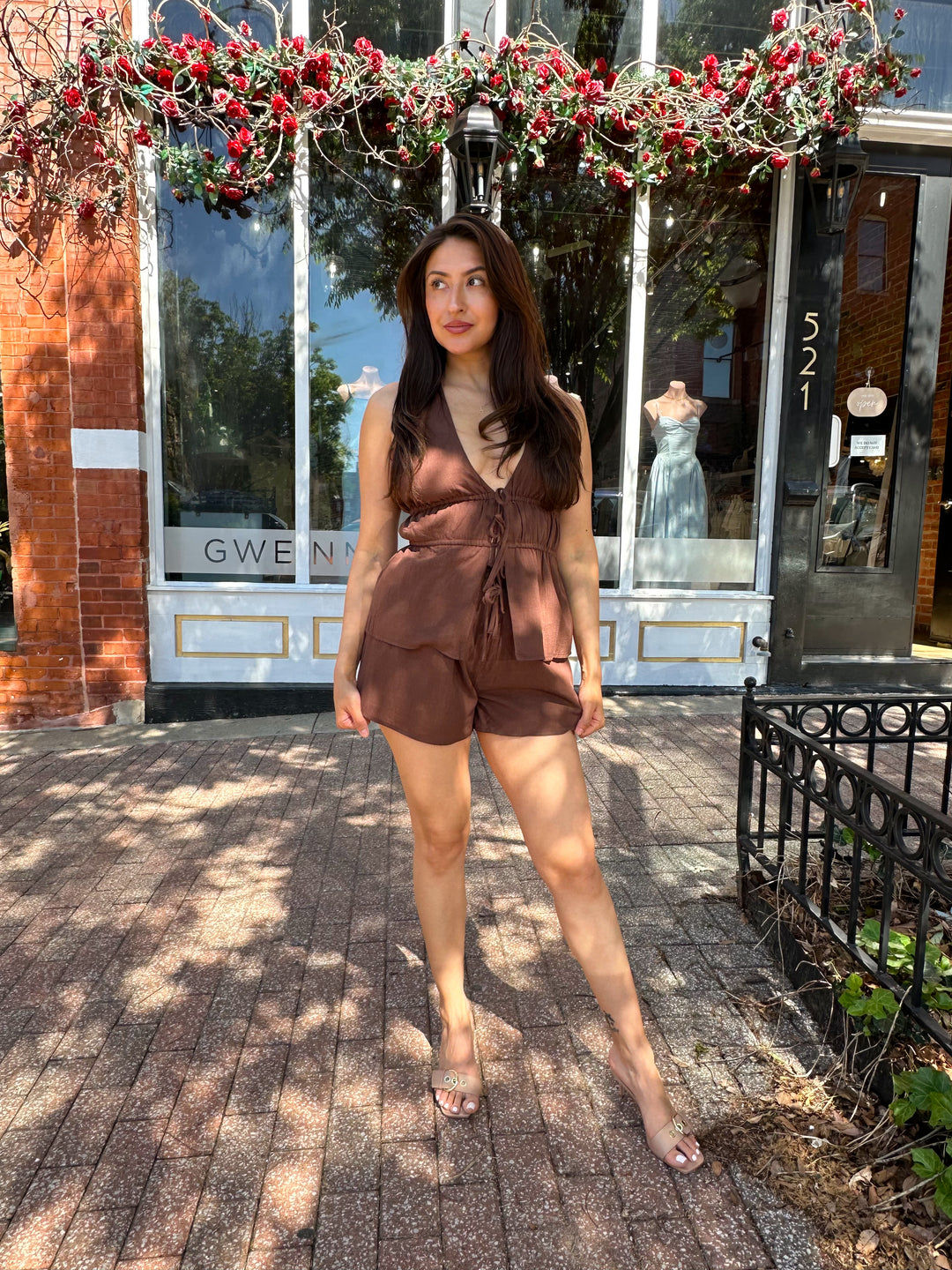 Woman wearing chocolate brown two piece set with front tie top, and shorts.  