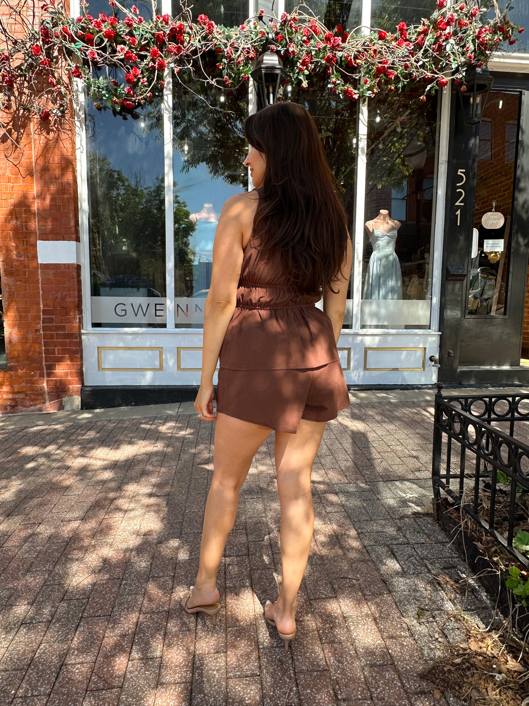 Woman wearing chocolate brown two piece set with front tie top, and shorts.  