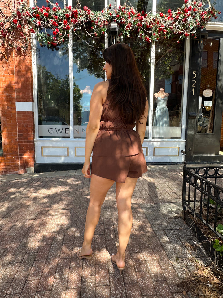 Woman wearing chocolate brown two piece set with front tie top, and shorts.  