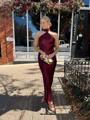 Woman wearing plum satin maxi dress with halter neckline.