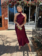Woman wearing plum satin maxi dress with halter neckline.