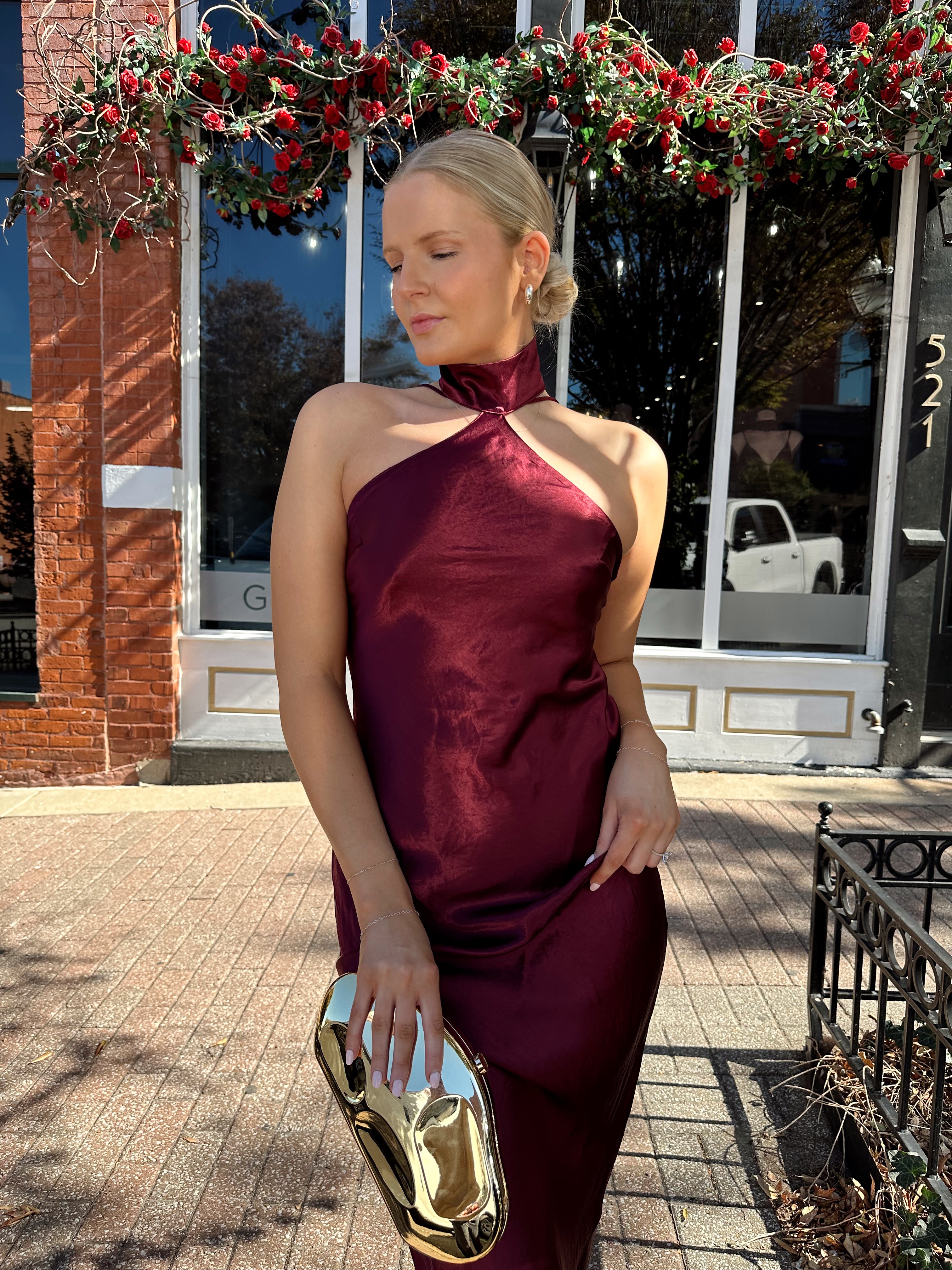 Woman wearing plum satin maxi dress with halter neckline.