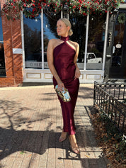 Woman wearing plum satin maxi dress with halter neckline.
