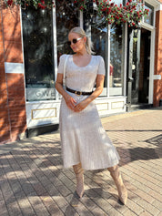 Woman wearing oatmeal cable knit sweater dress with dark belt. 