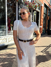Woman wearing oatmeal cable knit sweater dress with dark belt. 