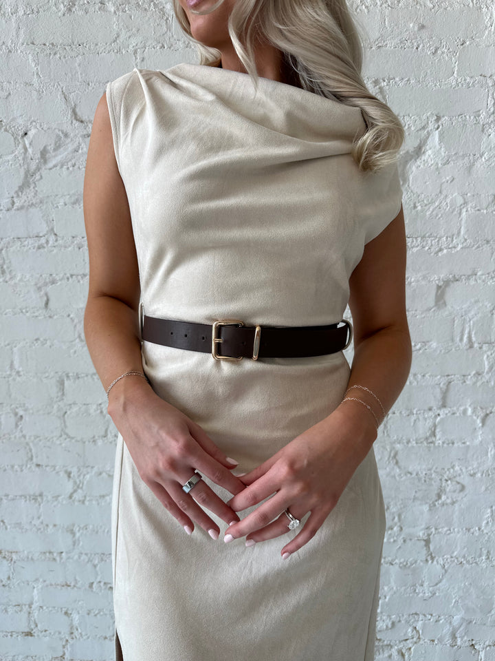 Woman wearing beige suede midi dress with belted waist and side slit. 