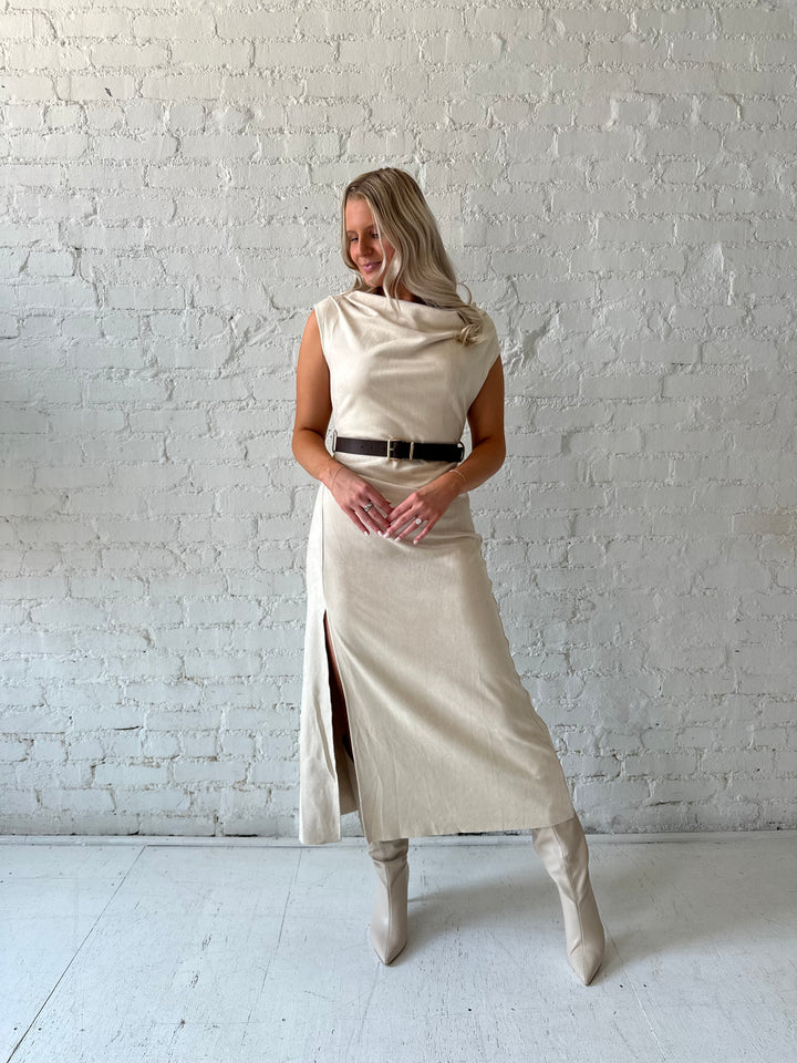 Woman wearing beige suede midi dress with belted waist and side slit. 