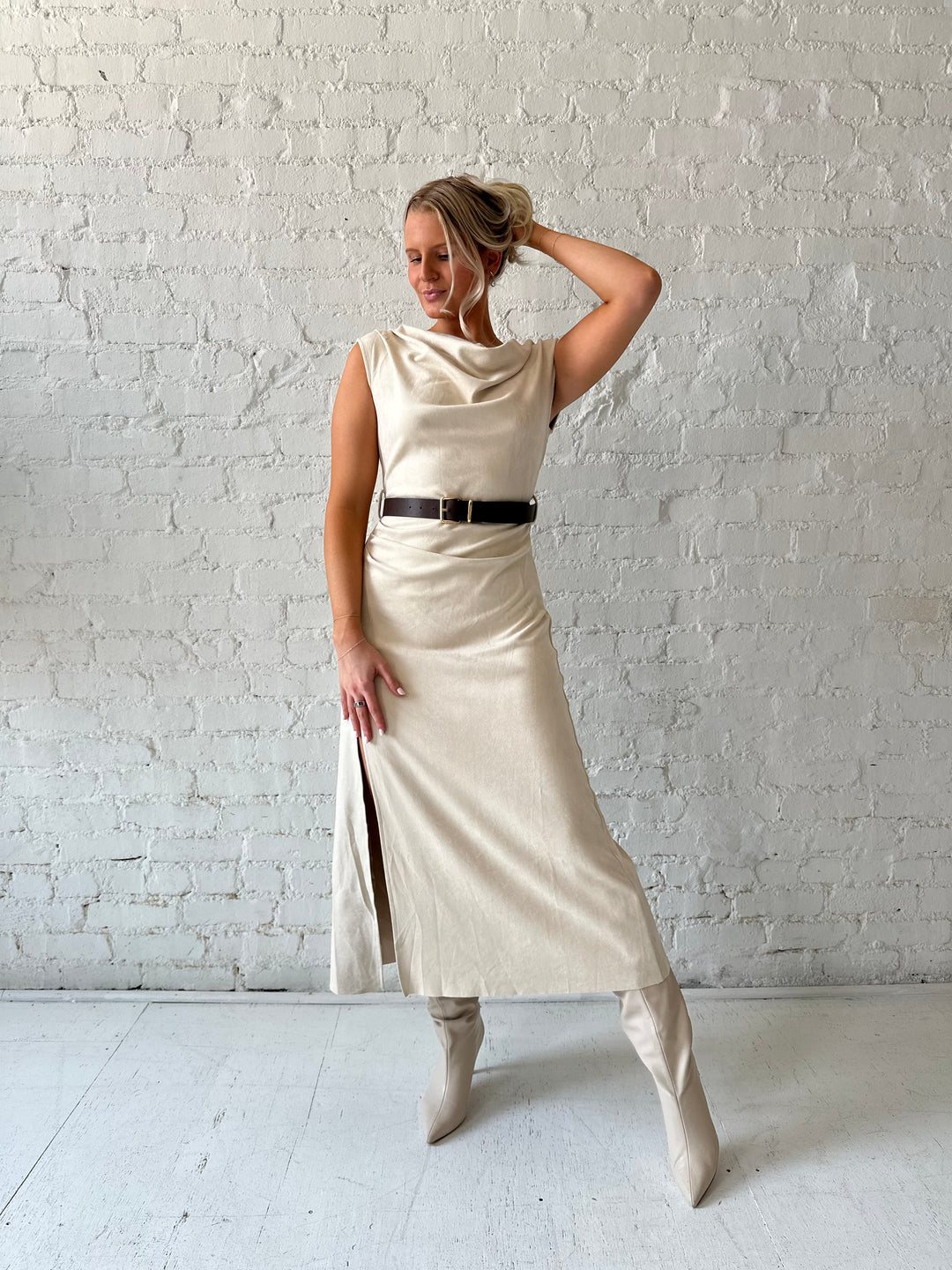 Woman wearing beige suede midi dress with belted waist and side slit. 