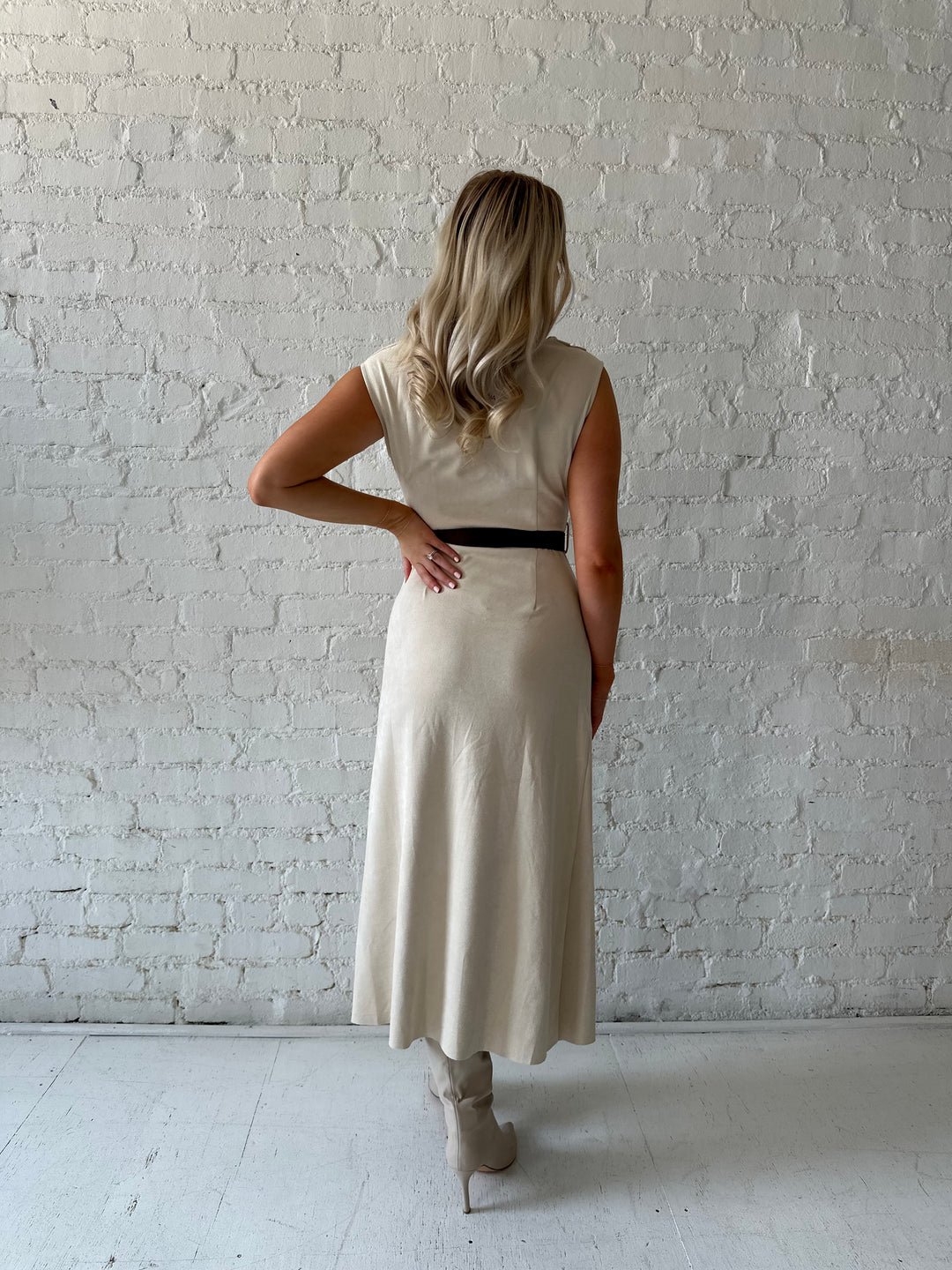Woman wearing beige suede midi dress with belted waist and side slit. 