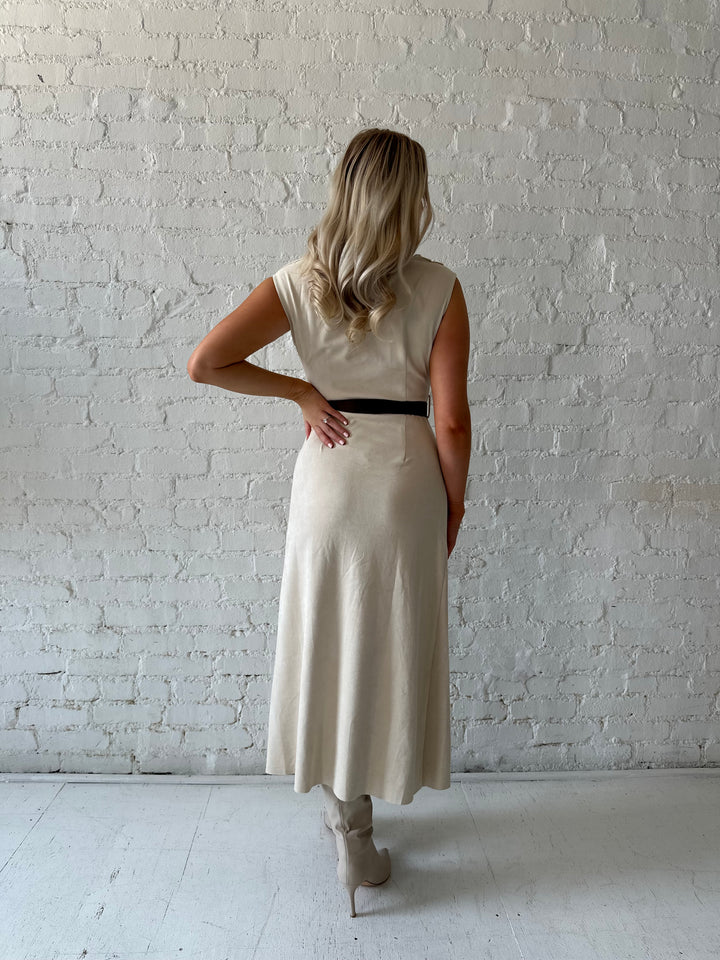 Woman wearing beige suede midi dress with belted waist and side slit. 
