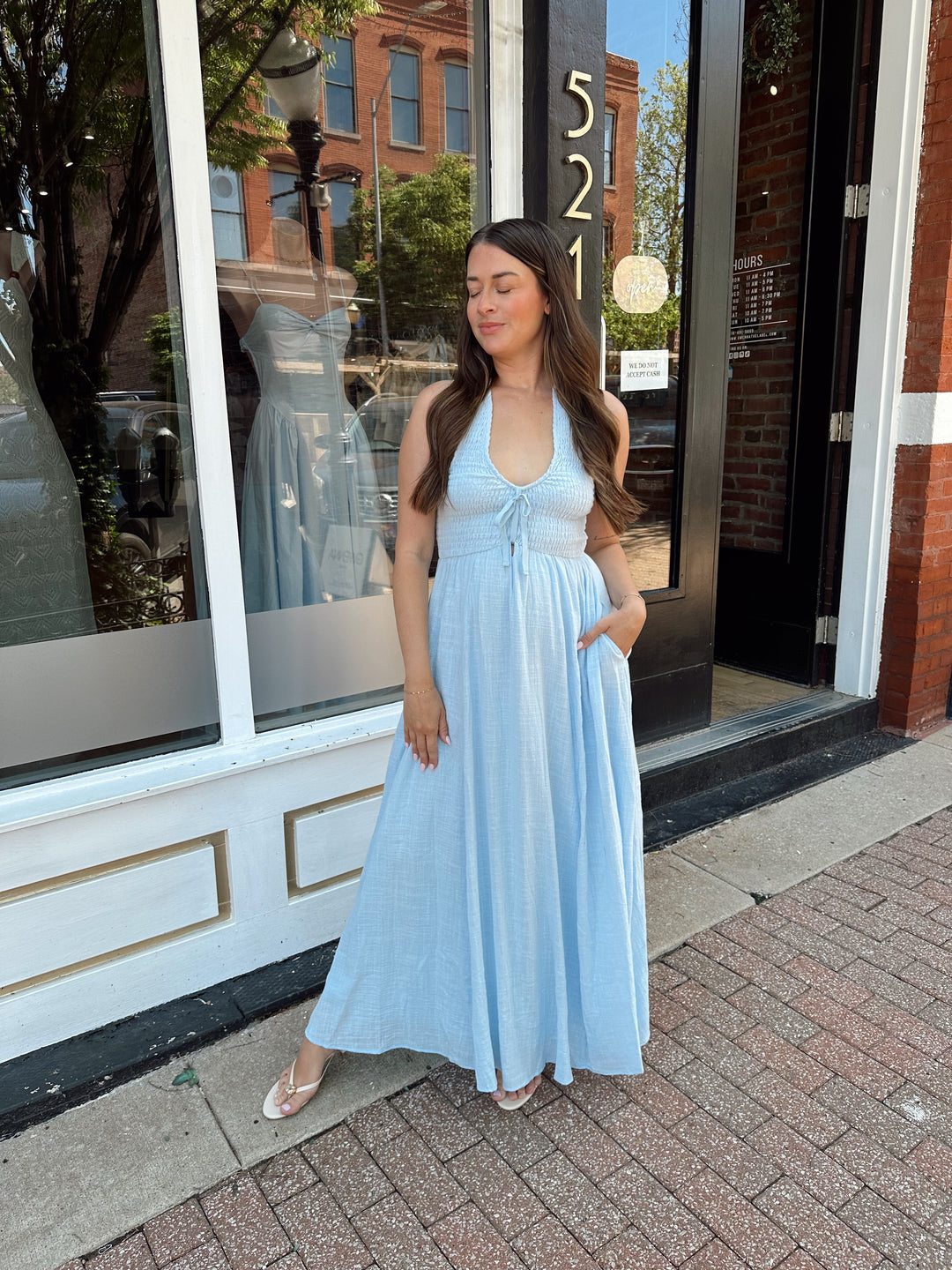 Woman wearing blue smocked midi dress with halter neck, tie detail, and pockets.