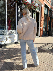 Woman wearing beige cable knit puff coat with light wash jean.