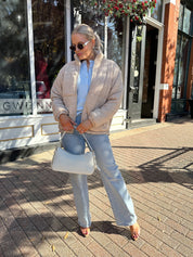 Woman wearing beige cable knit puff coat with light wash jean.