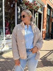 Woman wearing beige cable knit puff coat with light wash jean.