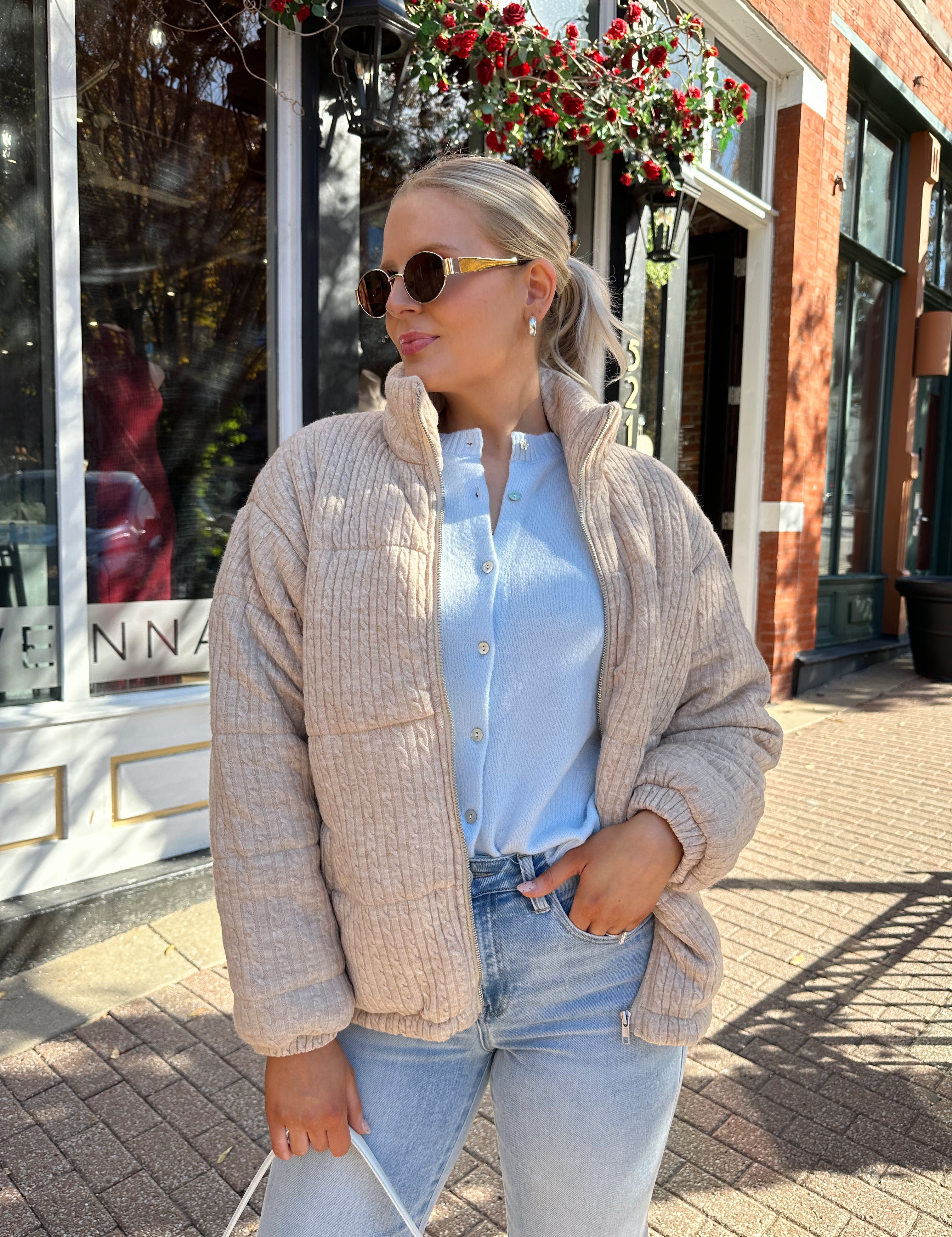Woman wearing beige cable knit puff coat with light wash jean.