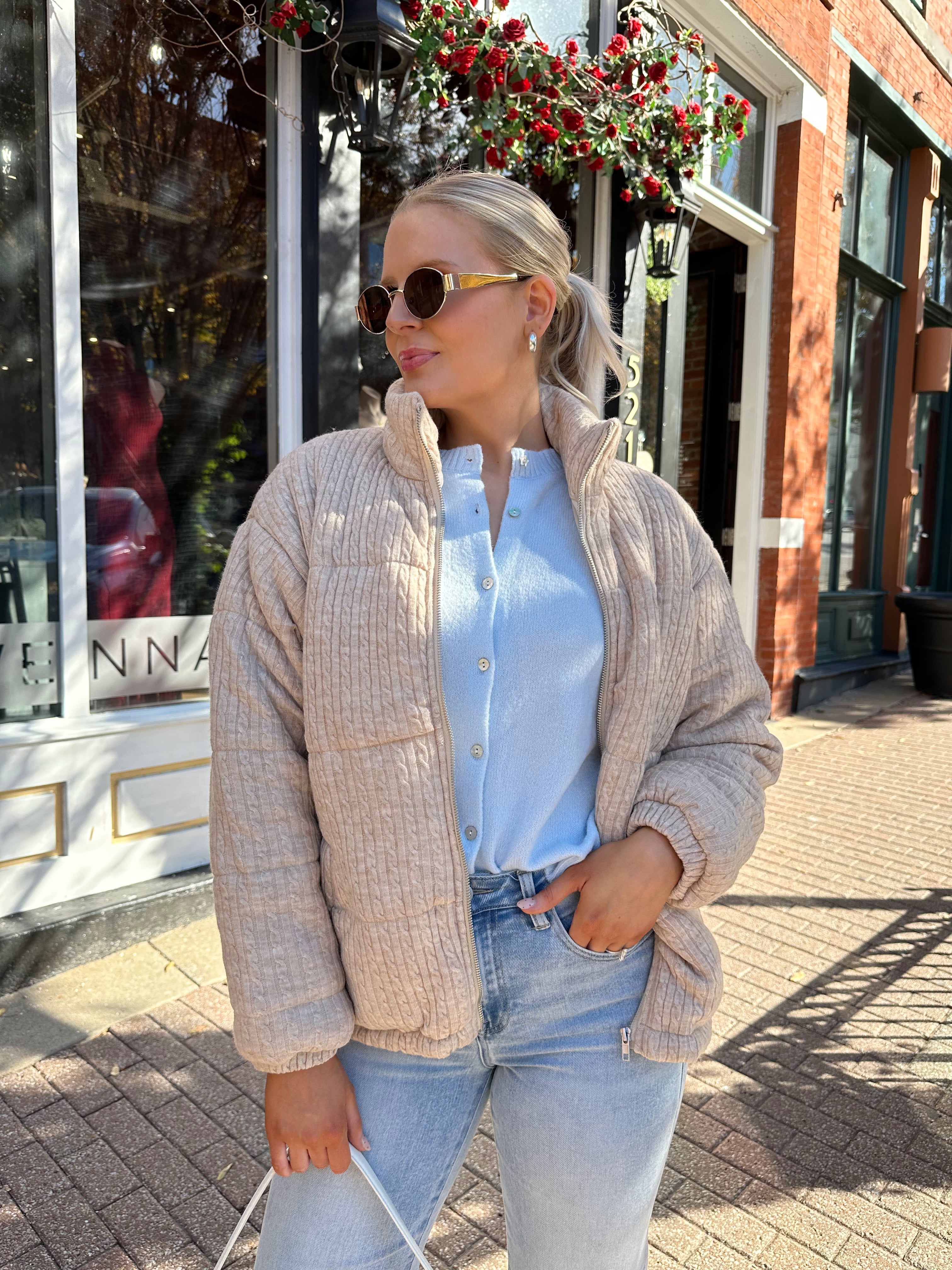 Woman wearing beige cable knit puff coat with light wash jean.
