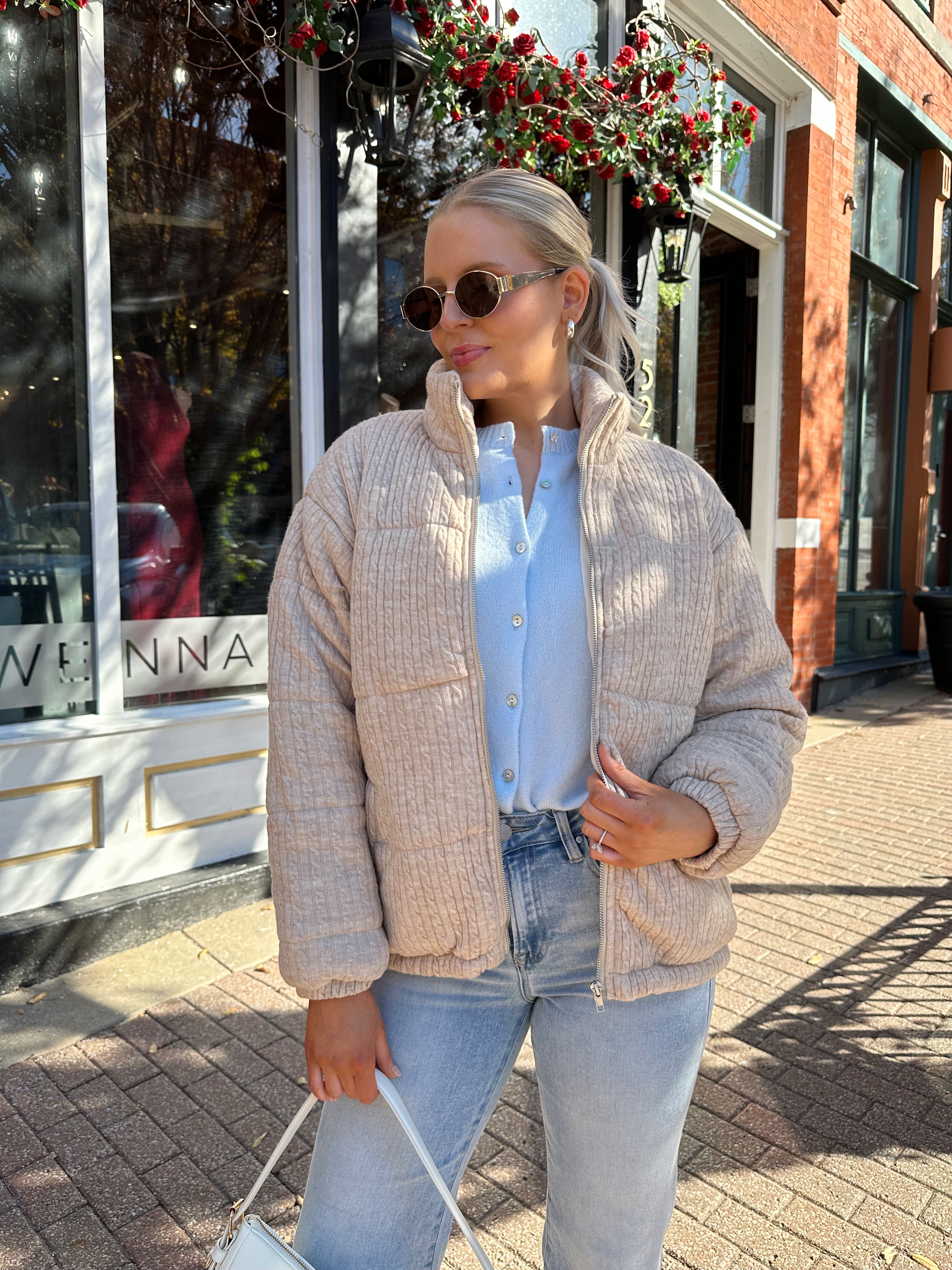 Woman wearing beige cable knit puff coat with light wash jean.