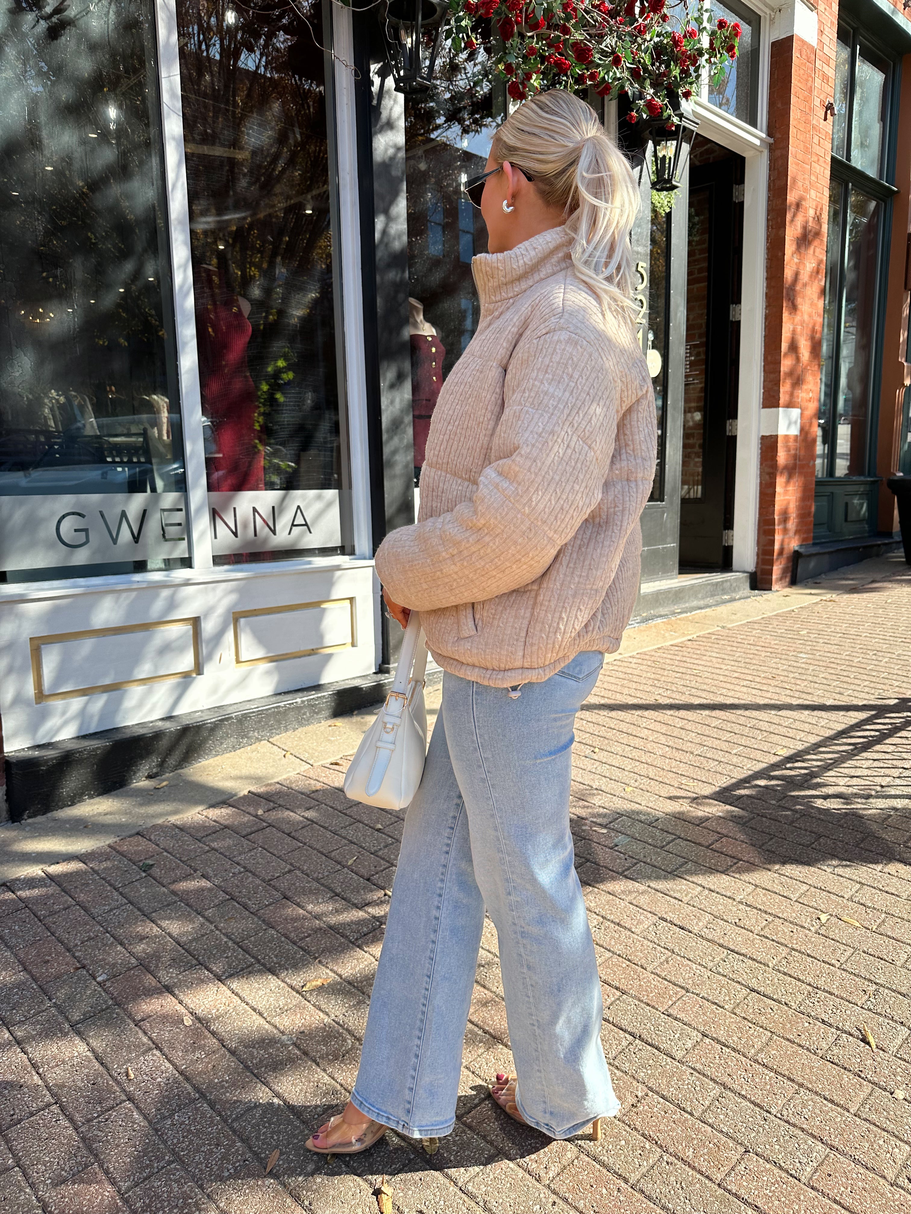Woman wearing beige cable knit puff coat with light wash jean.