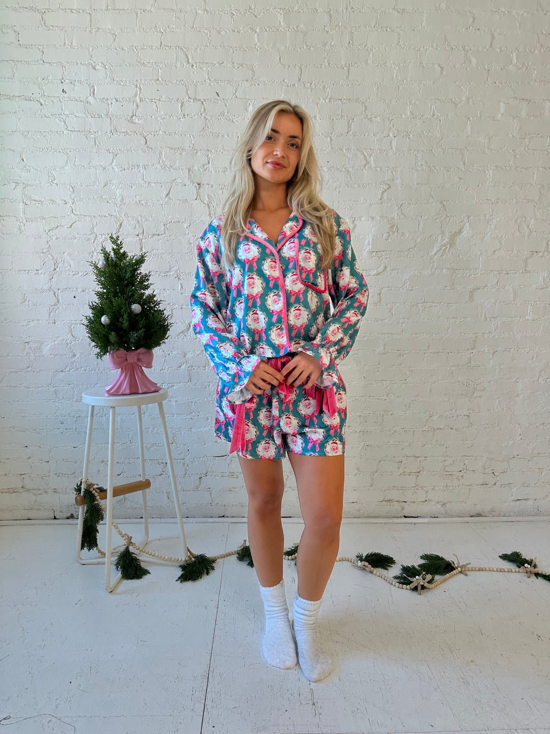 Woman wearing teal satin pajamas with santas all over. 