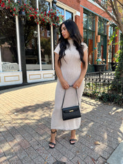 Woman wearing fitted taupe knit midi dress with short sleeves. 