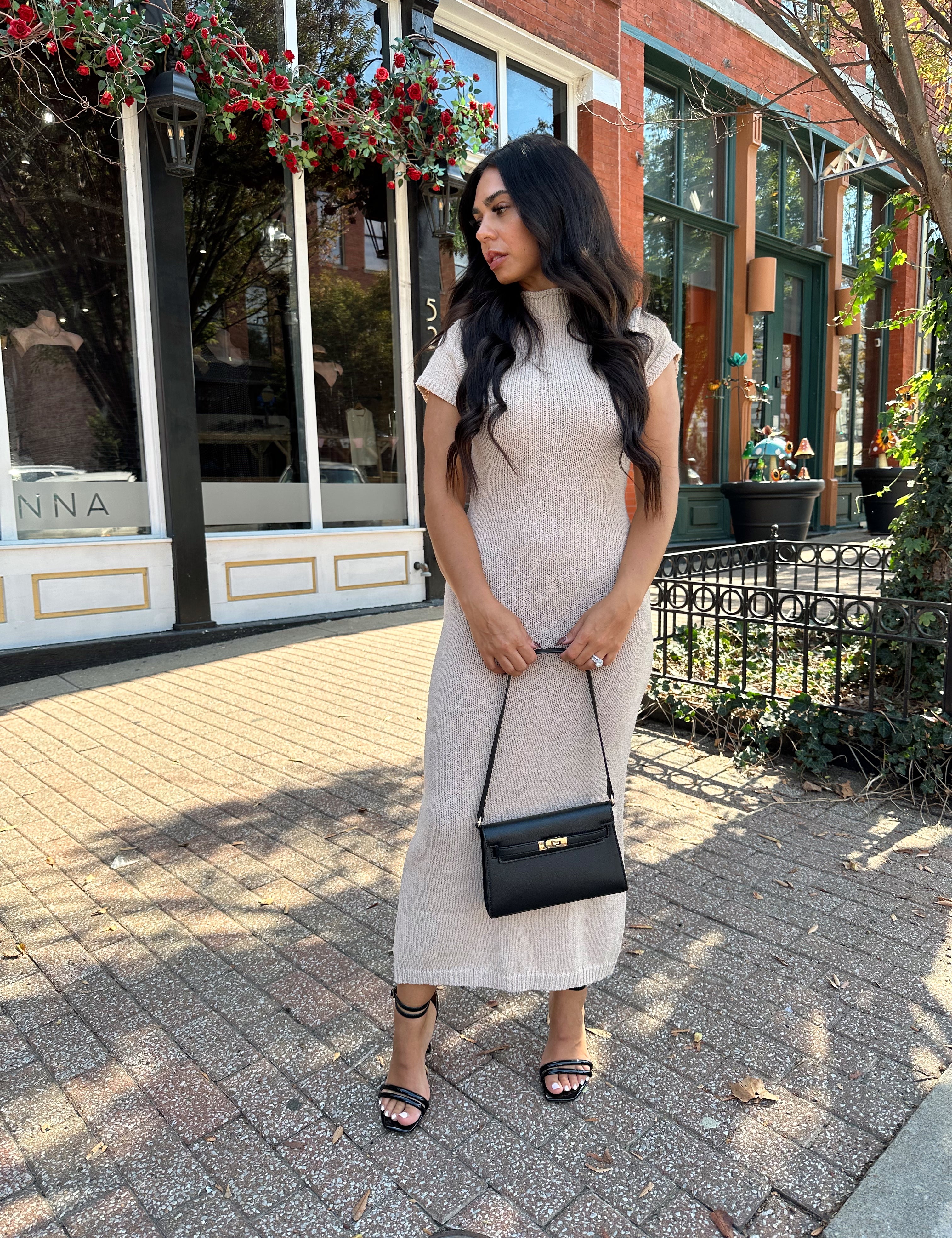 Woman wearing fitted taupe knit midi dress with short sleeves. 