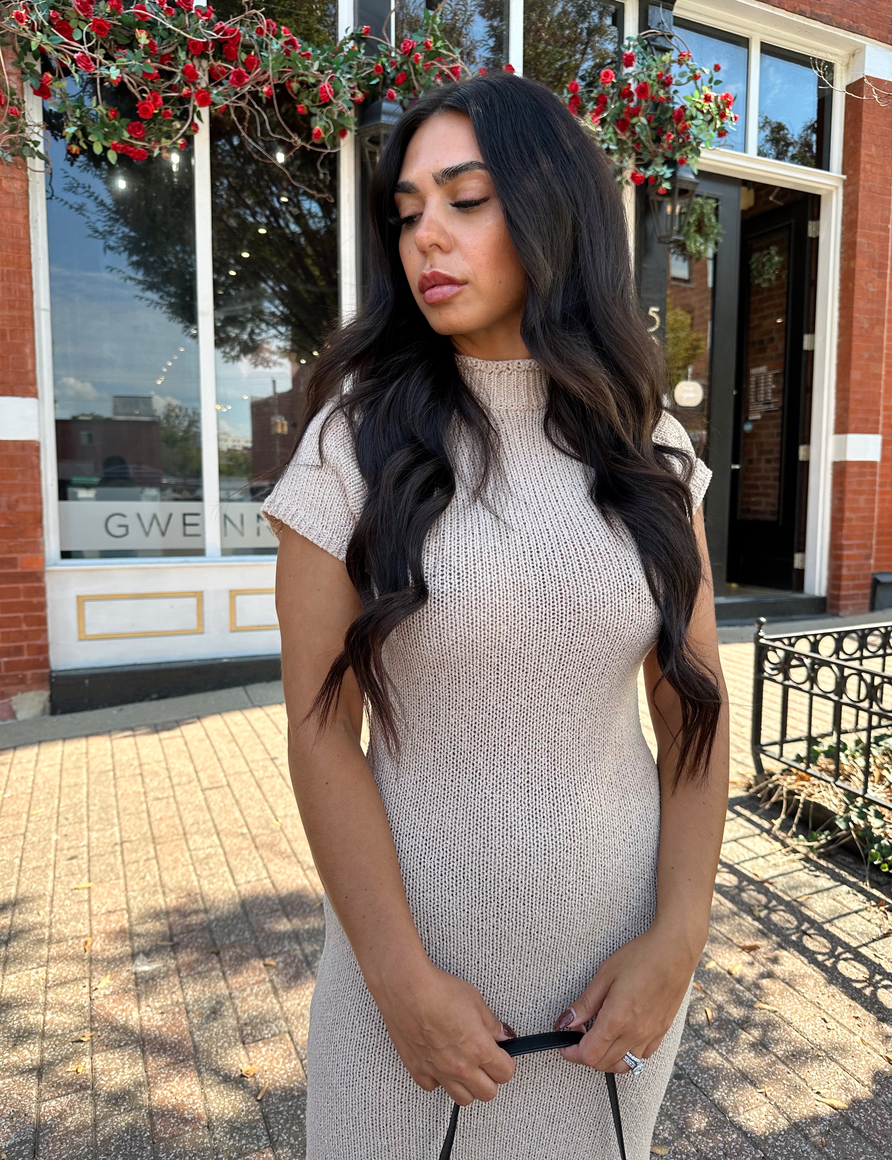 Woman wearing fitted taupe knit midi dress with short sleeves. 