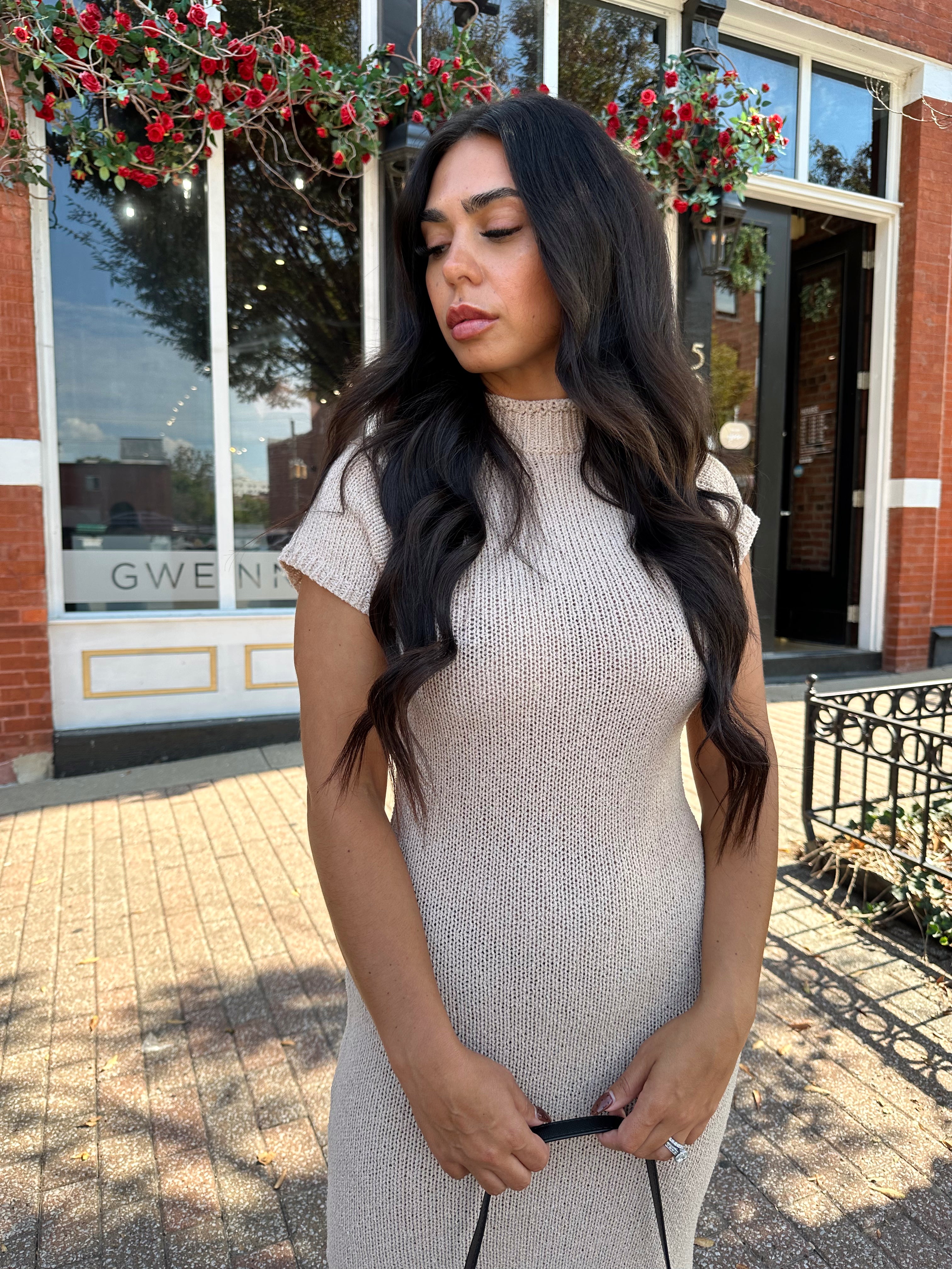 Woman wearing fitted taupe knit midi dress with short sleeves. 