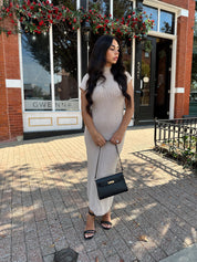 Woman wearing fitted taupe knit midi dress with short sleeves. 