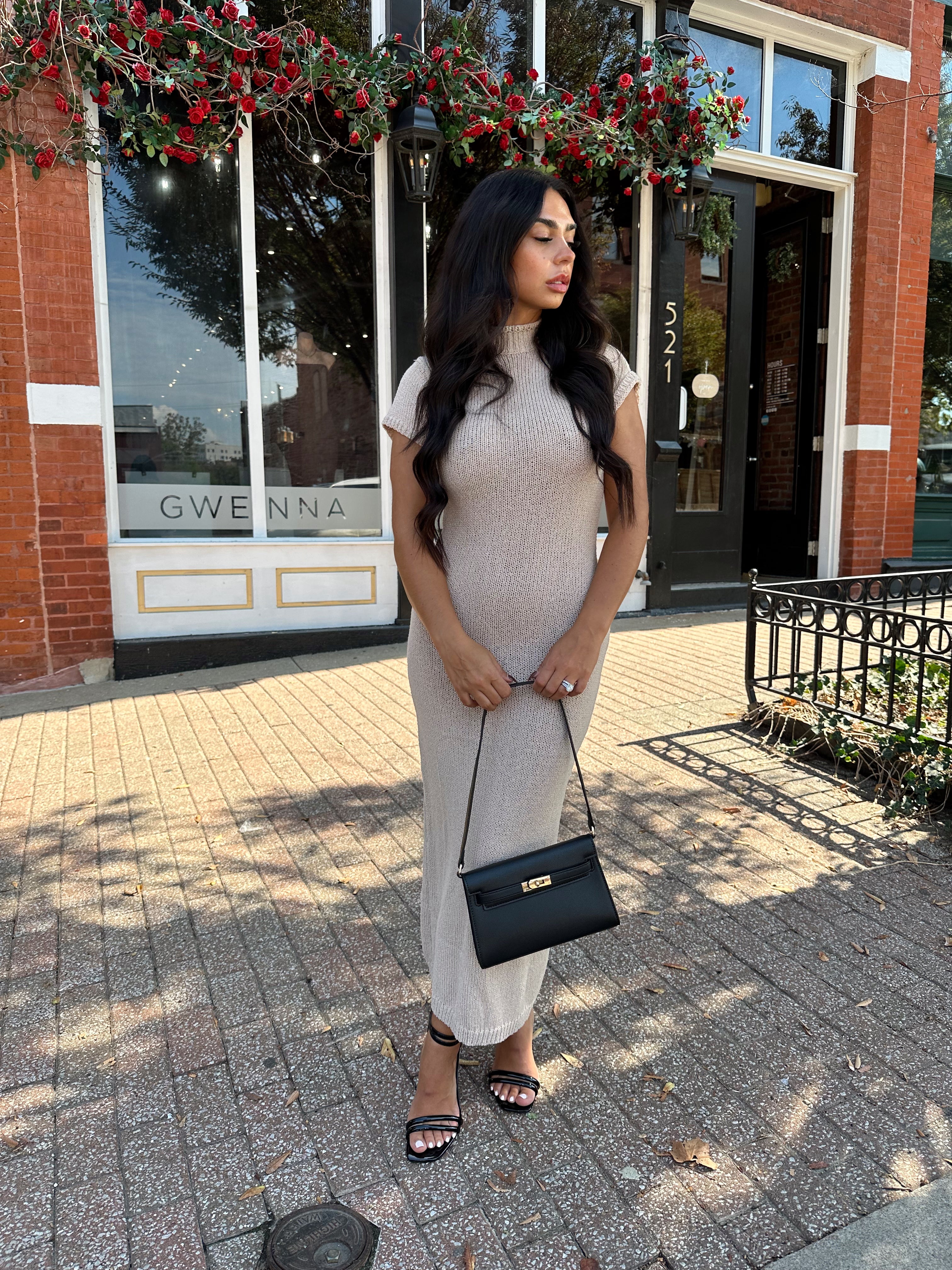 Woman wearing fitted taupe knit midi dress with short sleeves. 
