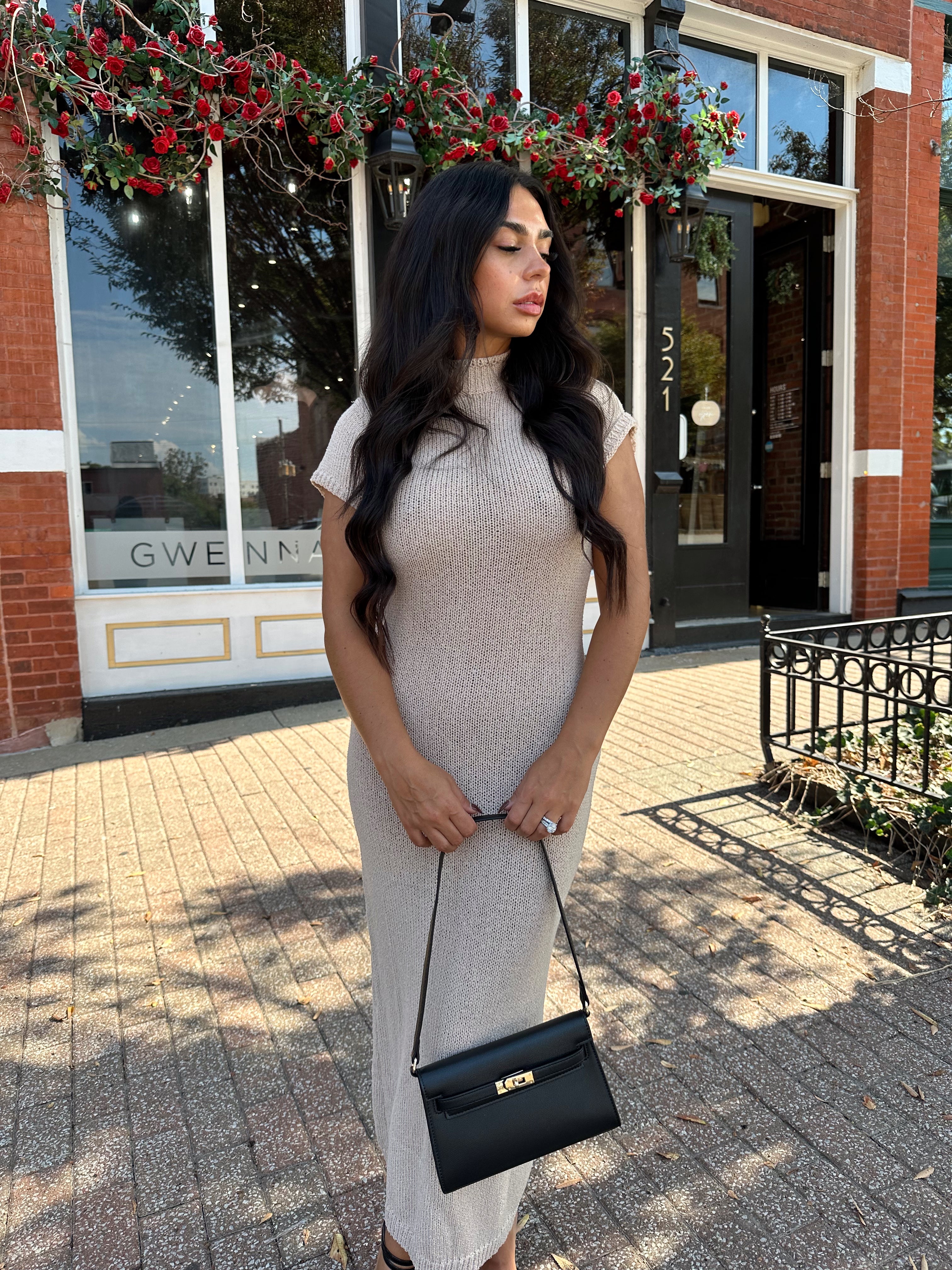 Woman wearing fitted taupe knit midi dress with short sleeves. 