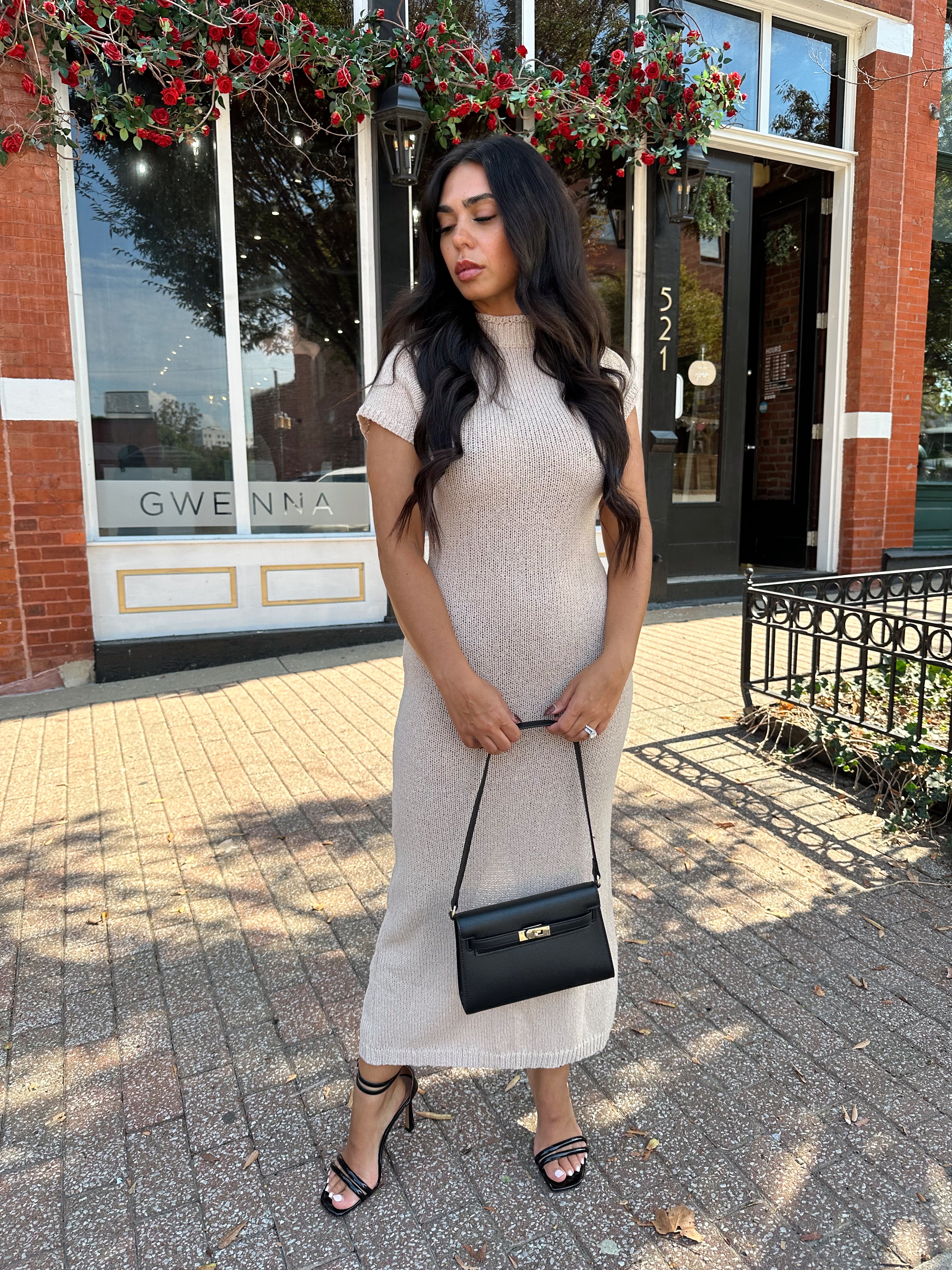Woman wearing fitted taupe knit midi dress with short sleeves. 