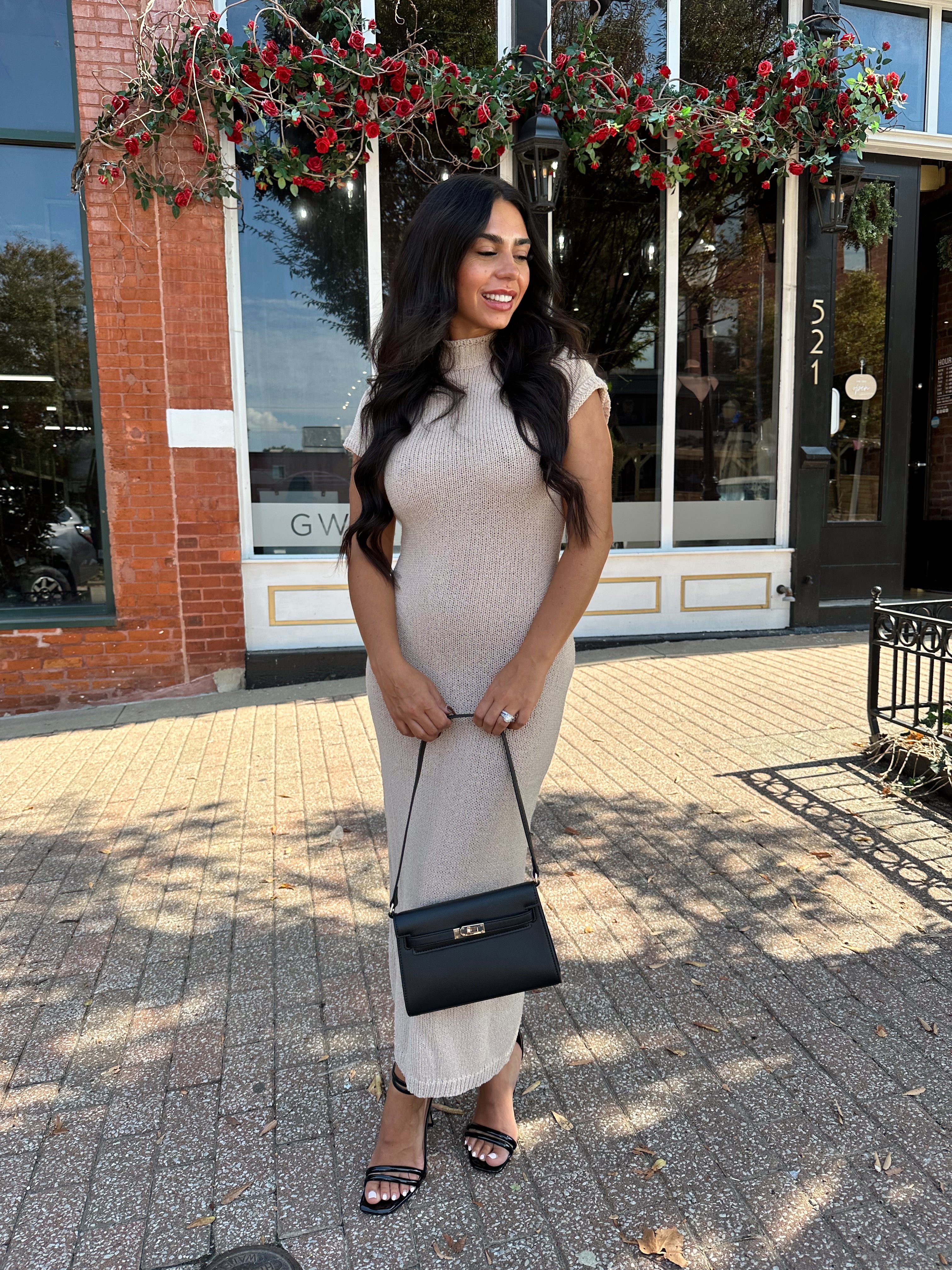 Woman wearing fitted taupe knit midi dress with short sleeves. 