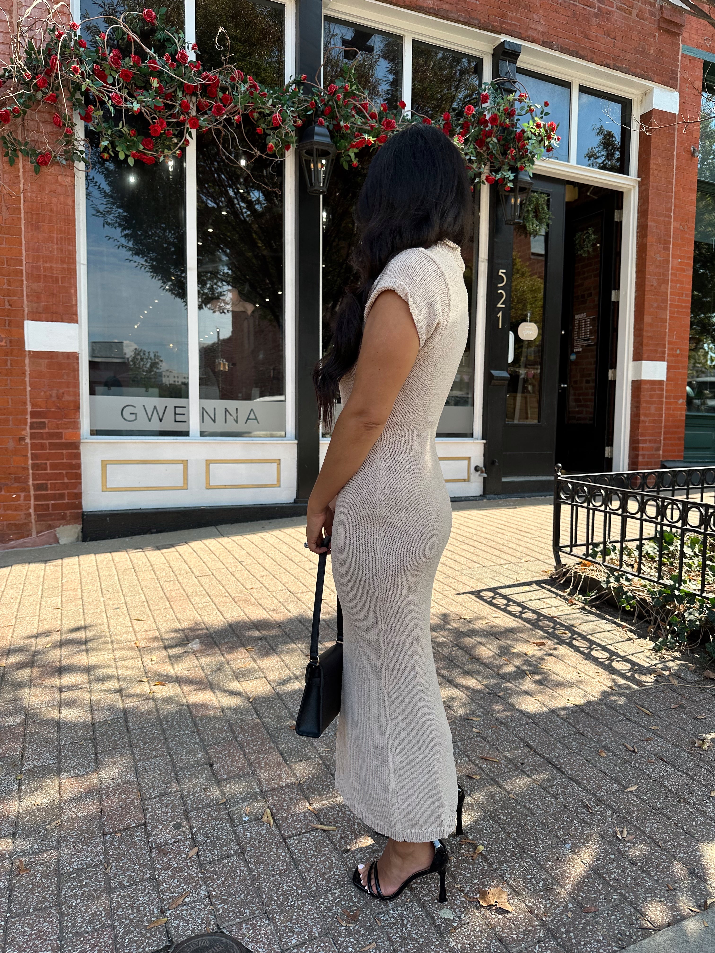 Woman wearing fitted taupe knit midi dress with short sleeves. 