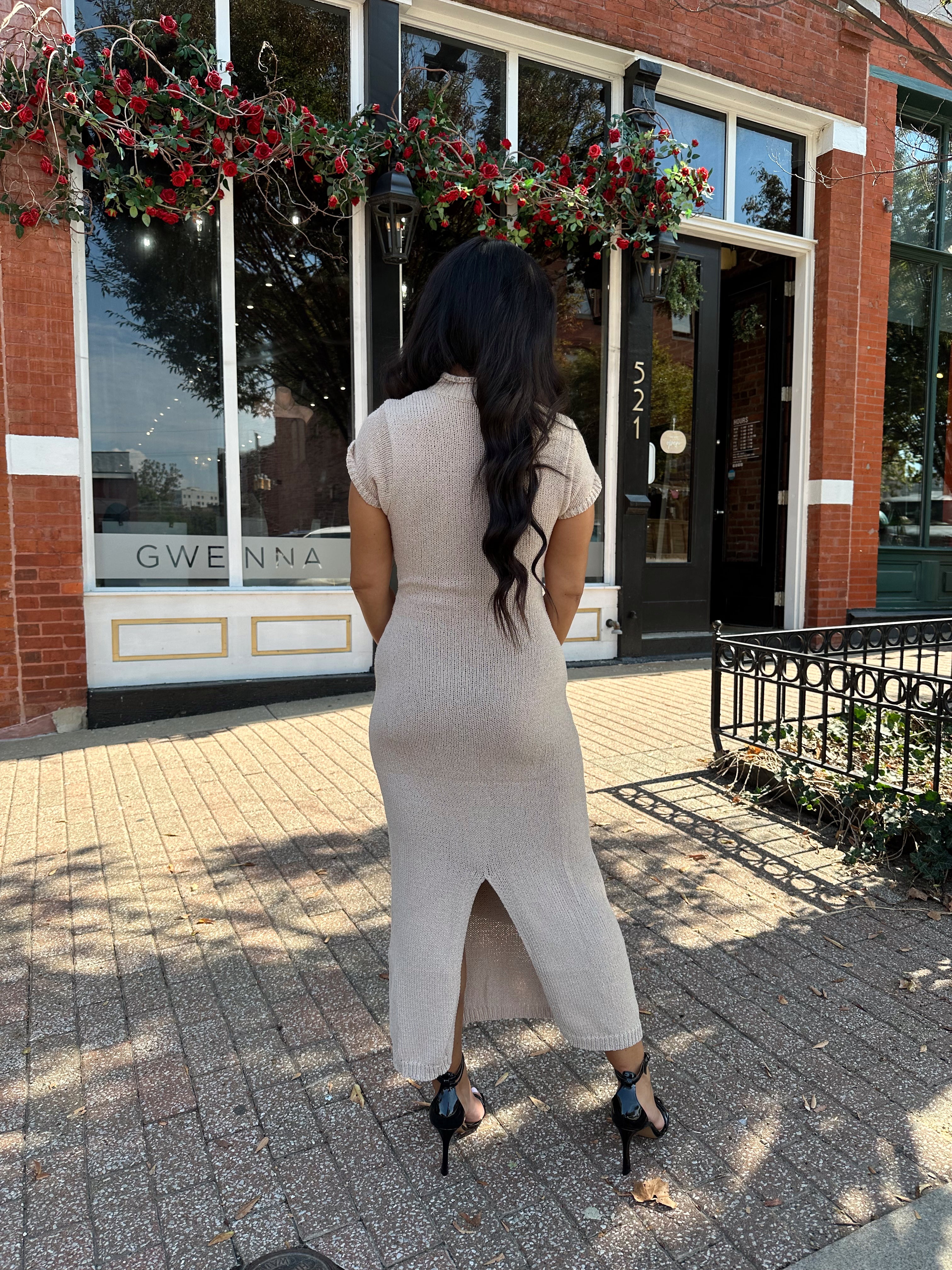 Woman wearing fitted taupe knit midi dress with short sleeves. 