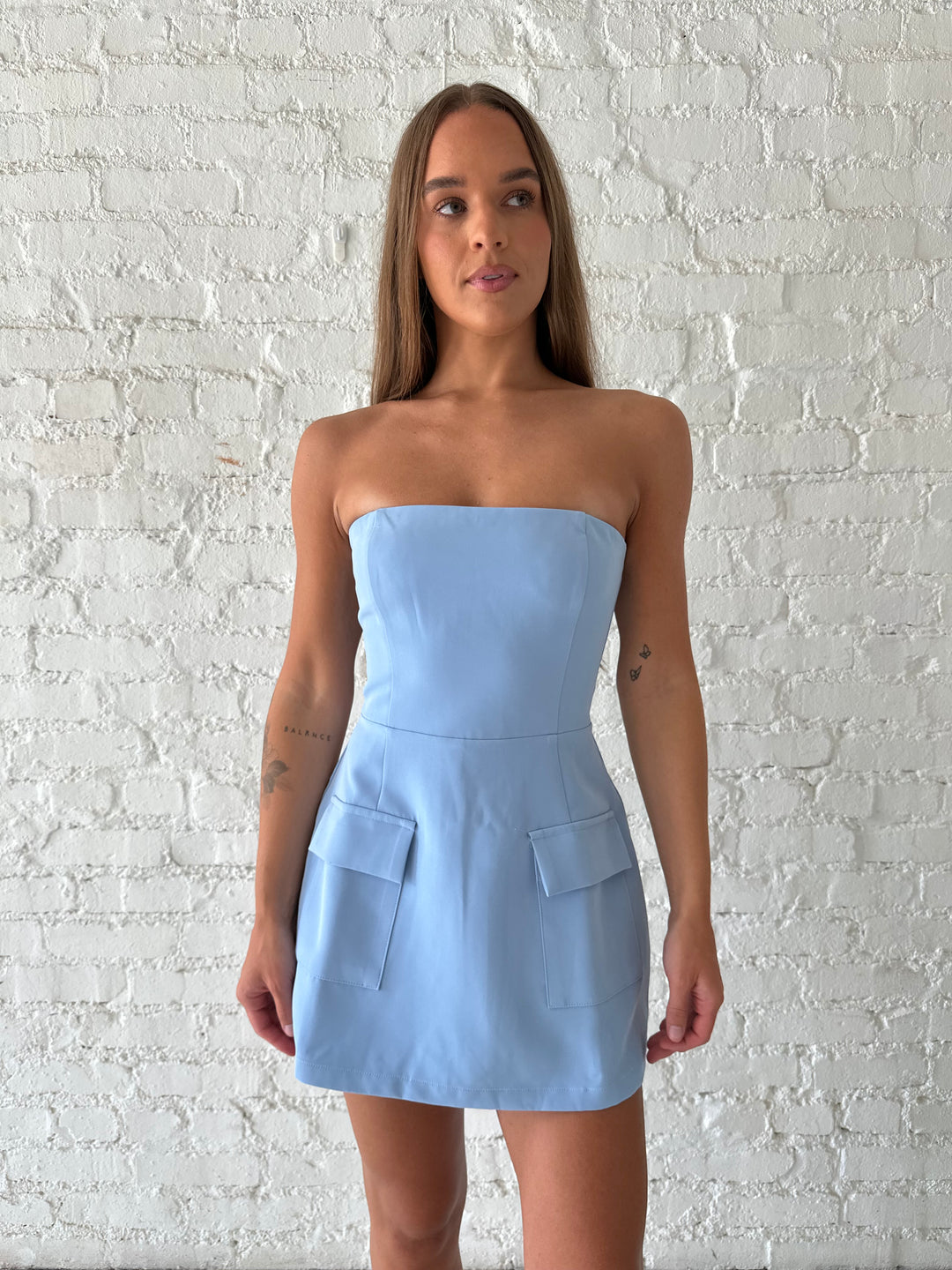 Woman wearing light blue strapless tailored mini dress.