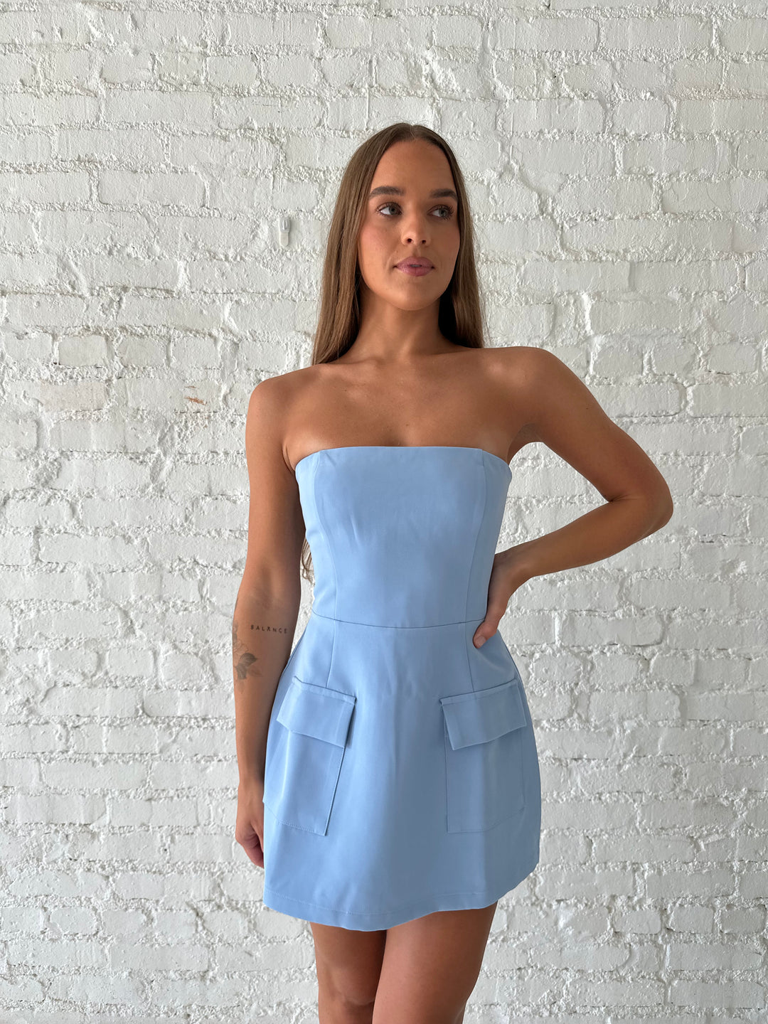 Woman wearing light blue strapless tailored mini dress.