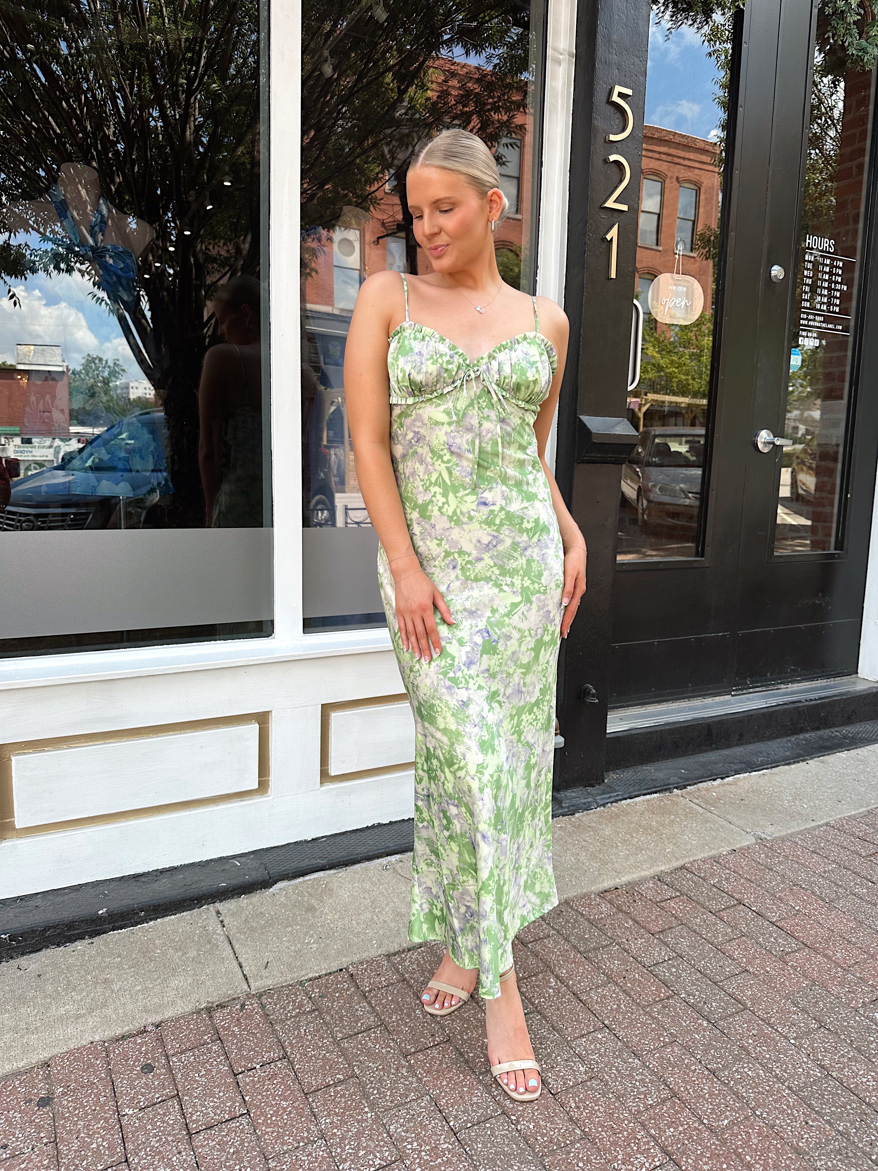 Green and purple floral satin midi dress with ruffle trim and tie detail.