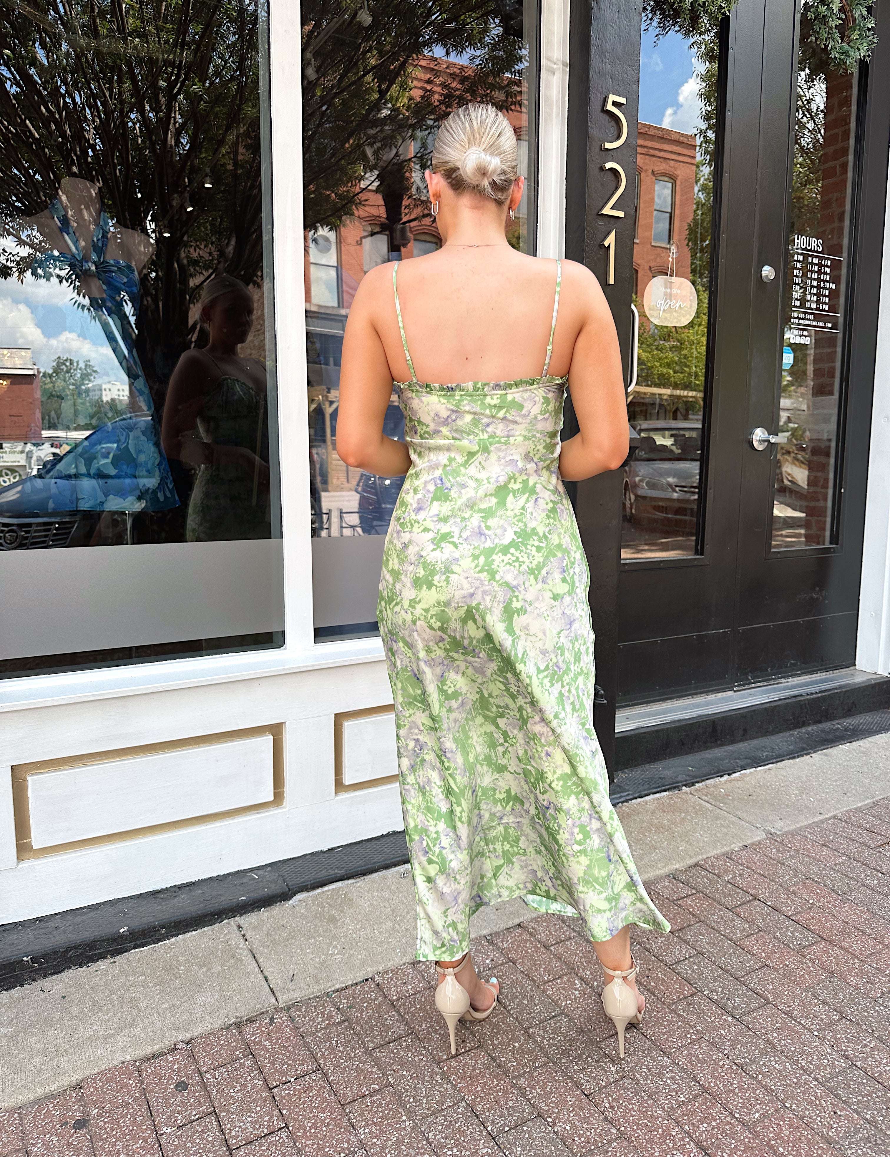 Green and purple floral satin midi dress with ruffle trim and tie detail.