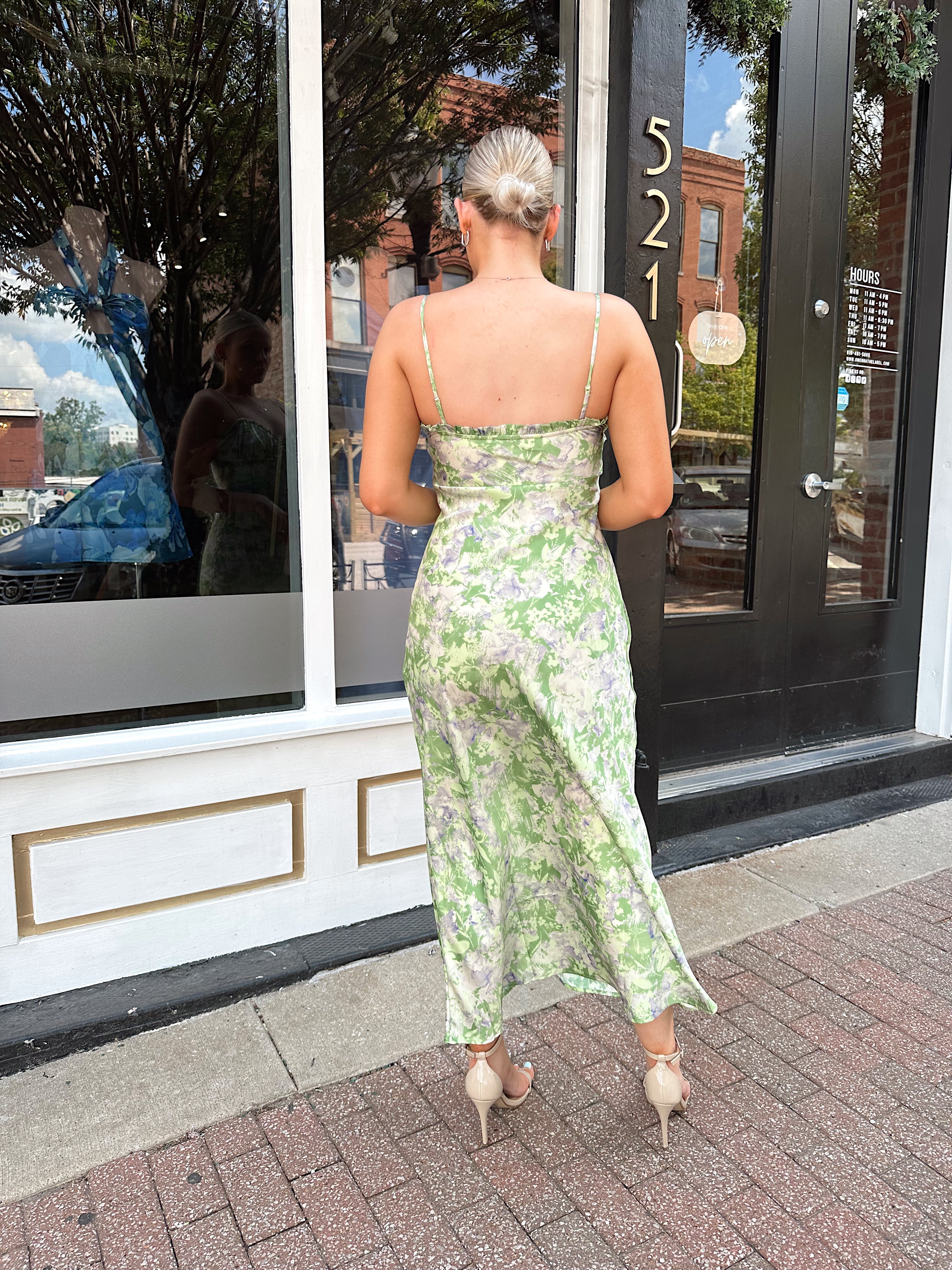 Green and purple floral satin midi dress with ruffle trim and tie detail.