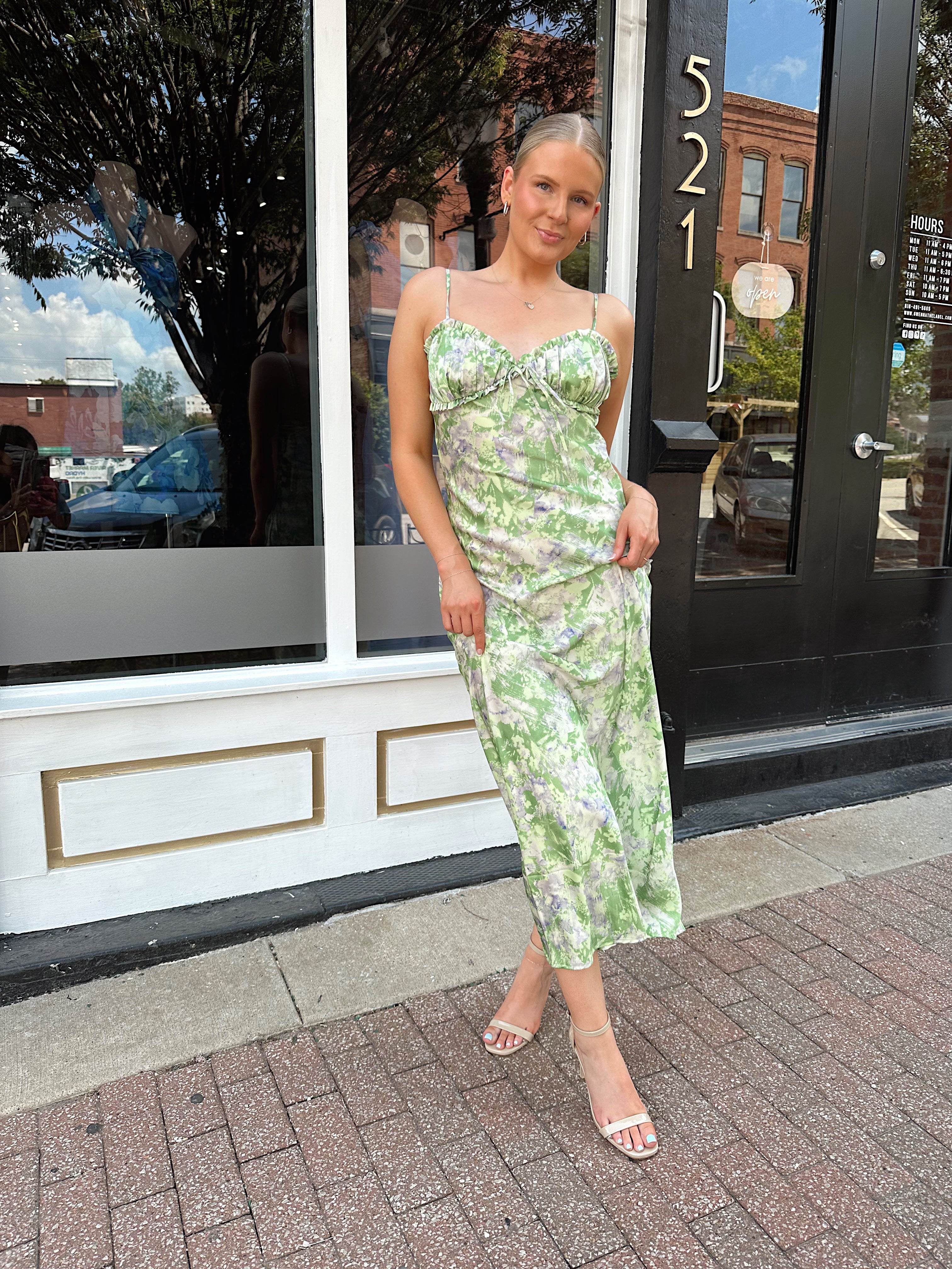 Green and purple floral satin midi dress with ruffle trim and tie detail.