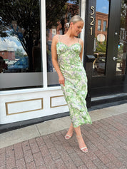 Green and purple floral satin midi dress with ruffle trim and tie detail.