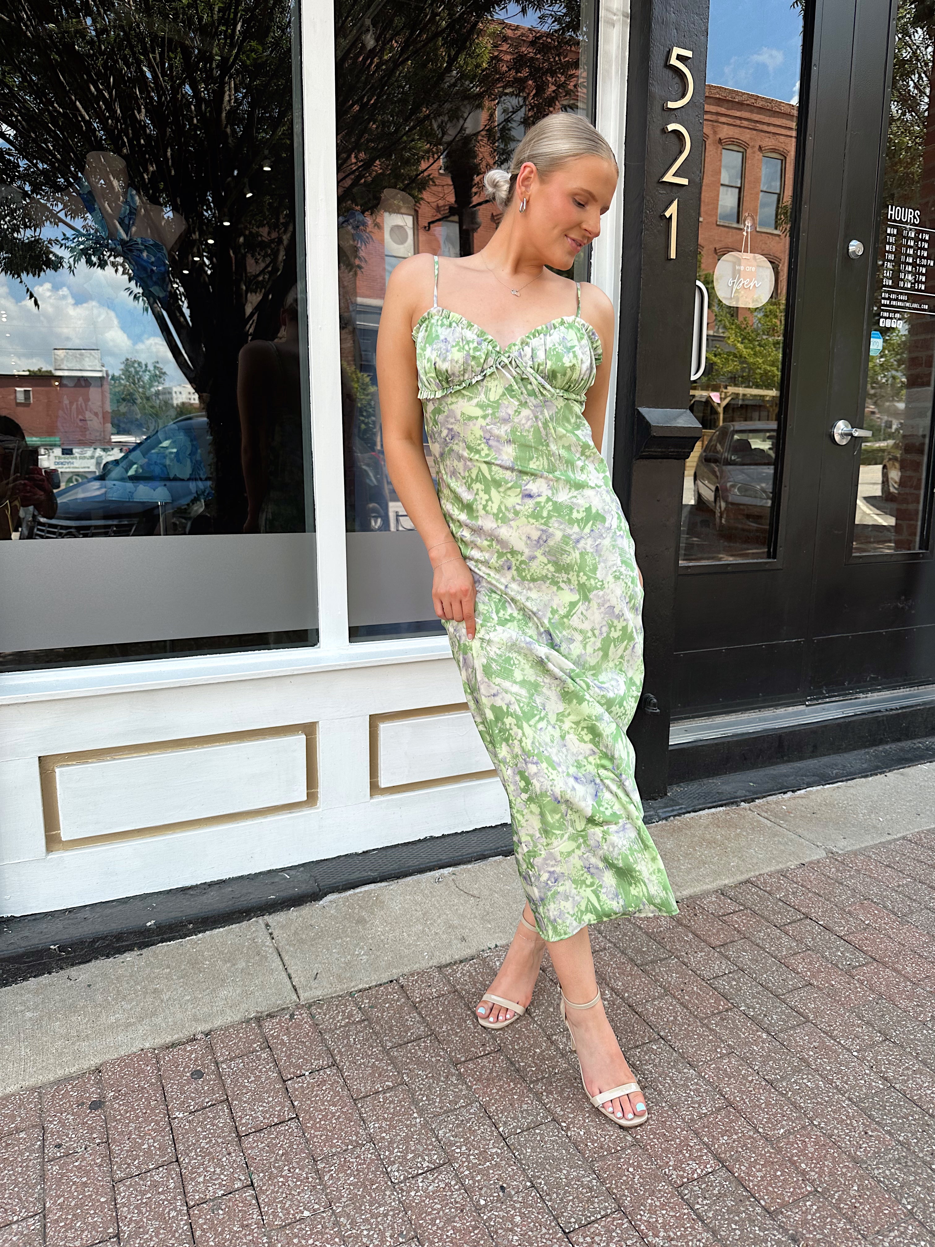 Green and purple floral satin midi dress with ruffle trim and tie detail.