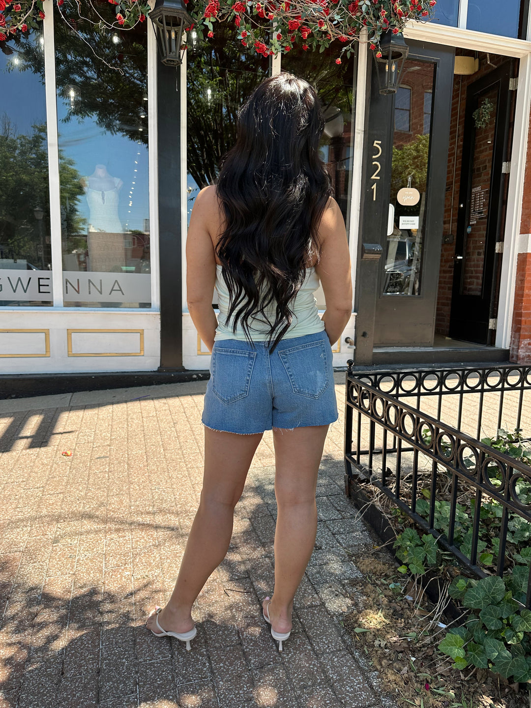 Woman wearing mint green, self tie halter top with ring detailing, ruched sides, and cowl neckline. 