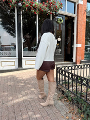 Woman wearing burgundy leather short with functional pockets and white top.
