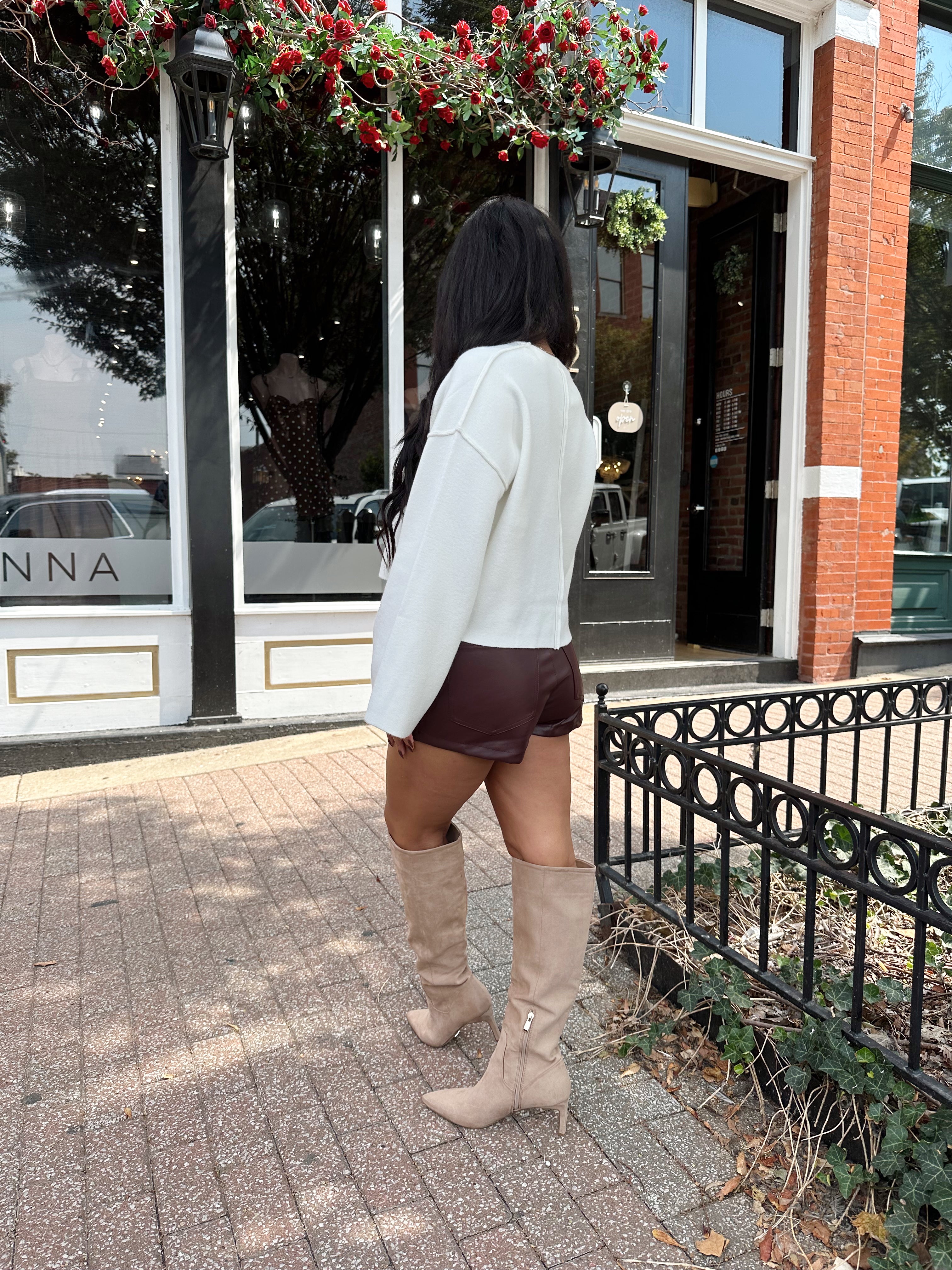 Woman wearing burgundy leather short with functional pockets and white top.